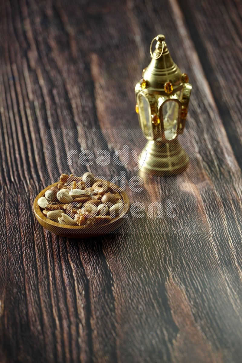 A golden lantern with drinks, dates, nuts, prayer beads and quran on brown wooden background