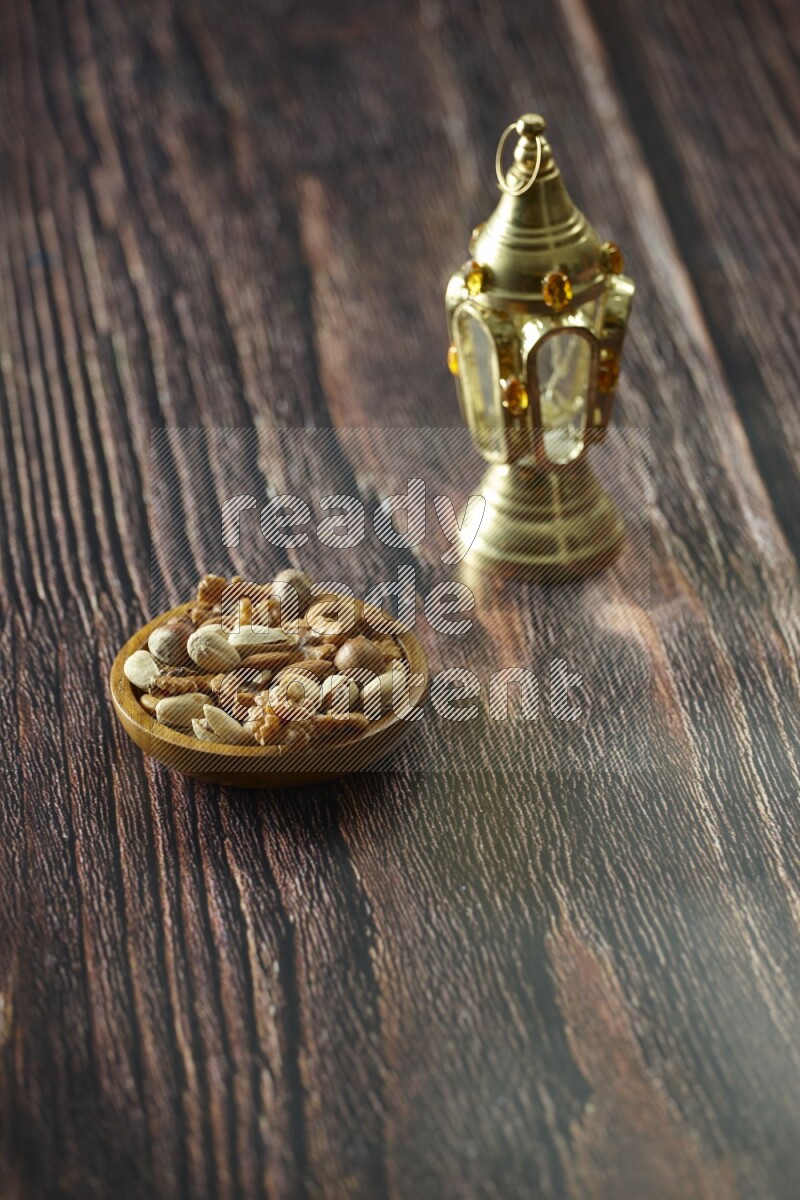 A golden lantern with different drinks, dates, nuts, prayer beads and quran on brown wooden background
