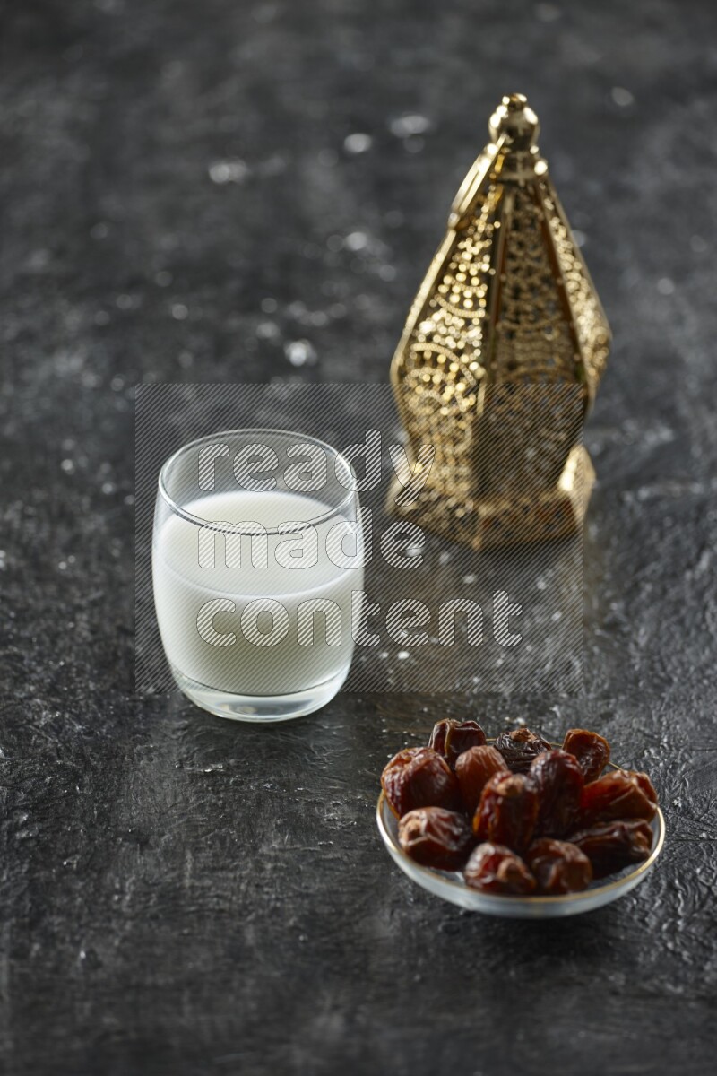 A golden lantern with different drinks, dates, nuts, prayer beads and quran on textured black background