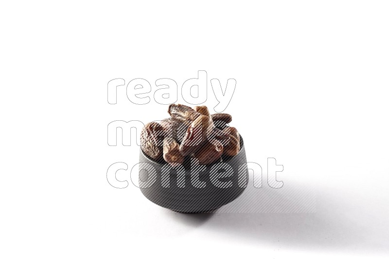 Dates in a black pottery bowl on white background
