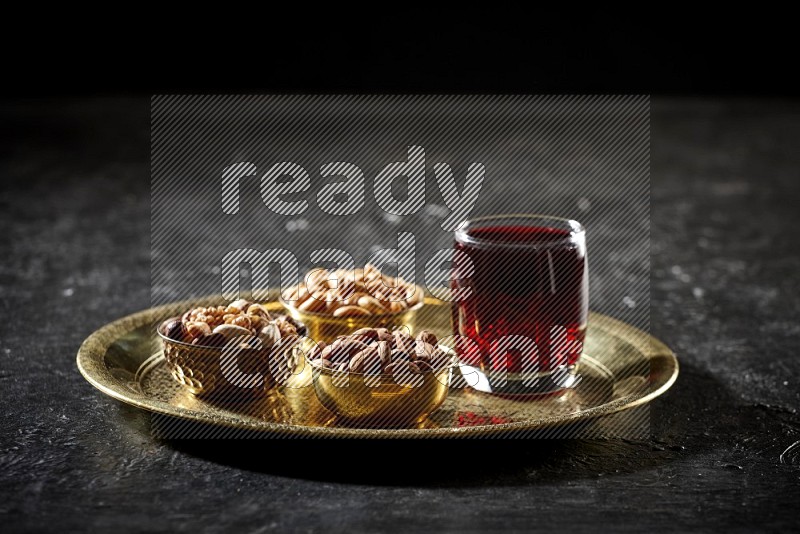 Nuts in metal bowls with Hibiscus on a tray in dark setup