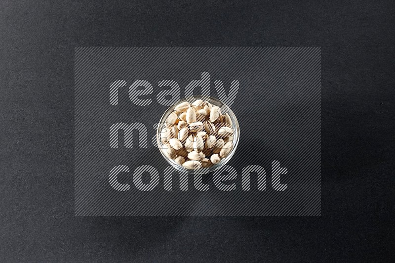 A glass bowl full of pistachios on a black background in different angles