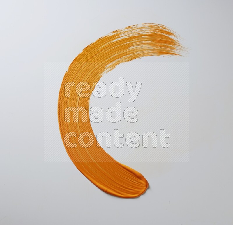 An orange half circular painting brush stroke on white background