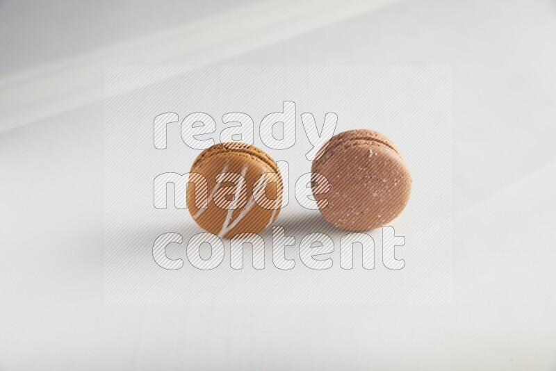 45º Shot of of two assorted Brown Irish Cream, and Brown Hazelnuts macarons on white background