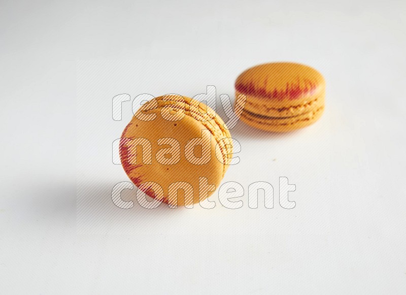 45º Shot of two orange Exotic macarons on white background