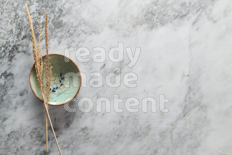 Wheat stalks on decorative pottery plate on grey marble background