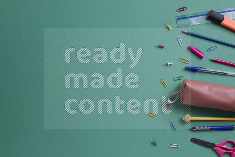 Different school supplies on green background