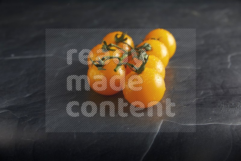 Yellow cherry tomato vein on a textured black slate background 45 degree