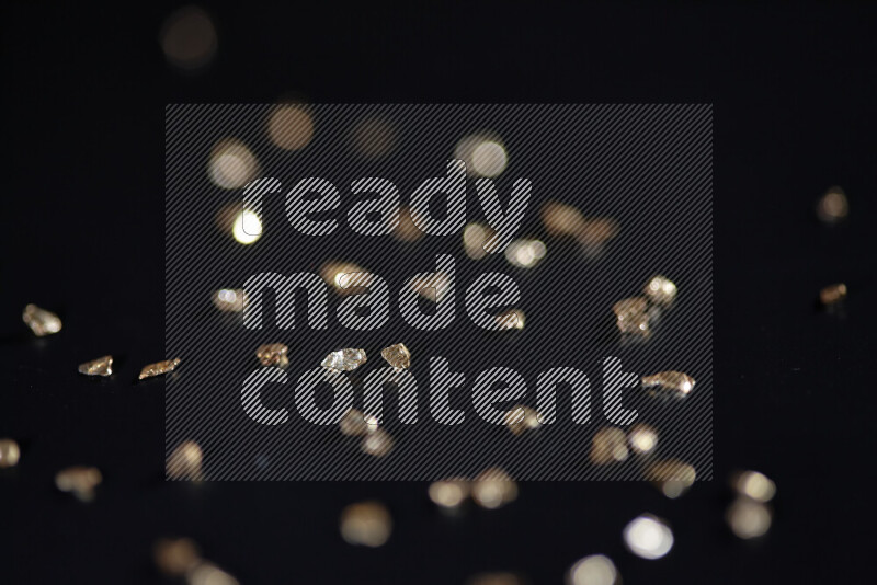 Gold shimmering fragments of glass scattered on a black background