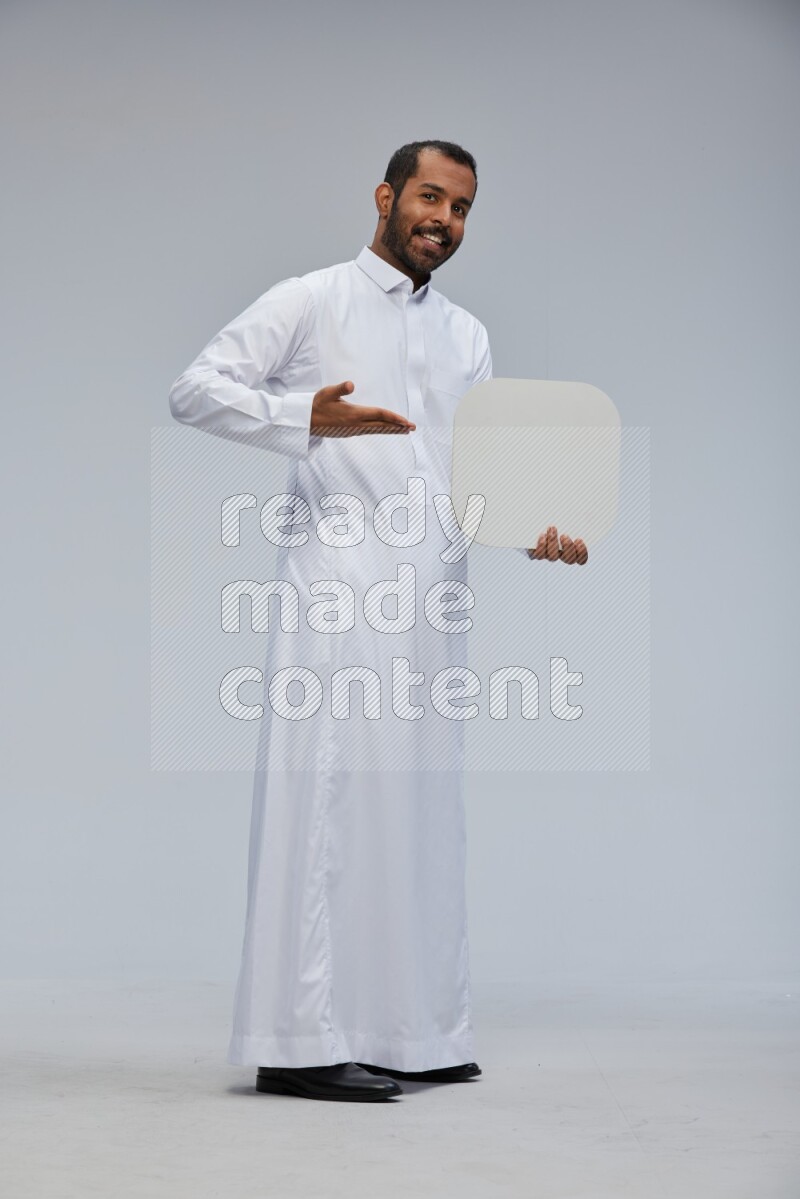 Saudi man wearing Thob standing holding social media sign on Gray background
