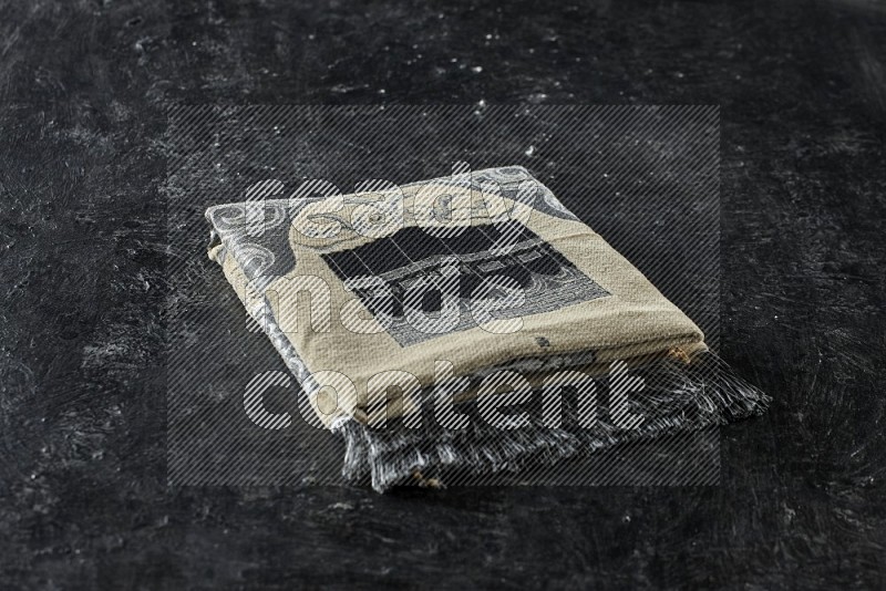 A prayer rug with different elements such as quran and prayer beads on black textured background