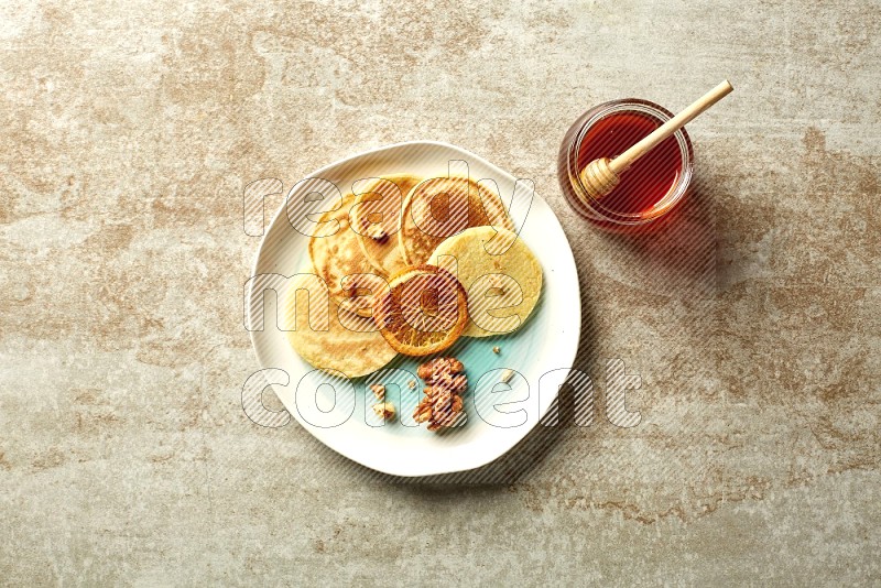 Five stacked dried orange mini pancakes in a bicolor plate on beige background