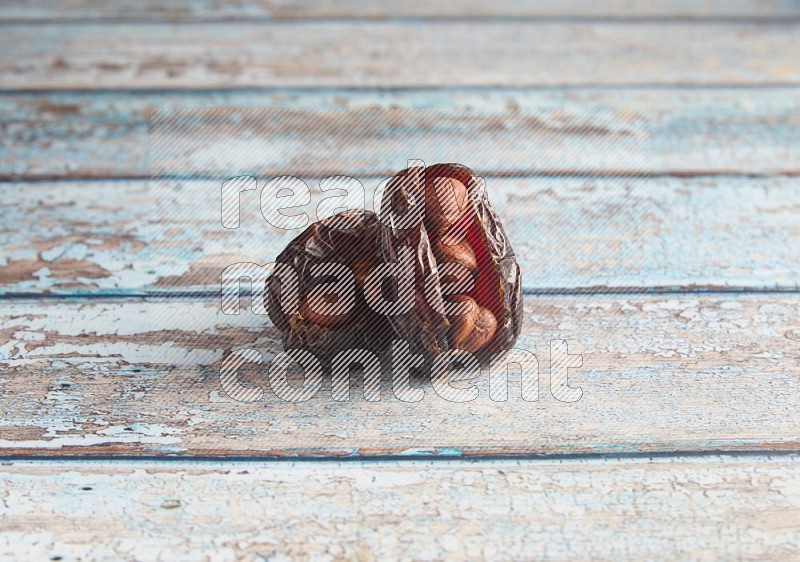 two hazelnuts stuffed madjoul dates on a light blue wooden background