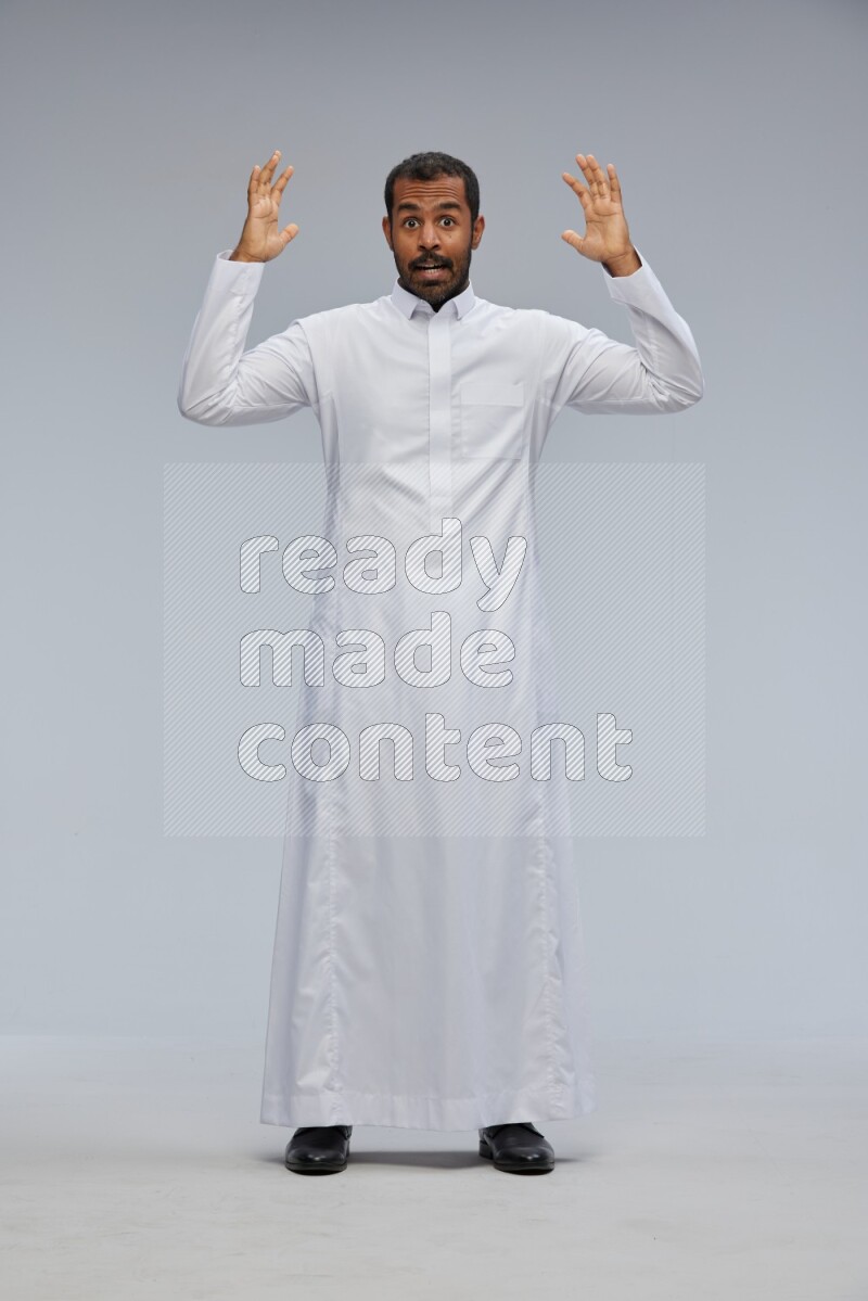 Saudi man Wearing Thob standing interacting with the camera on Gray background