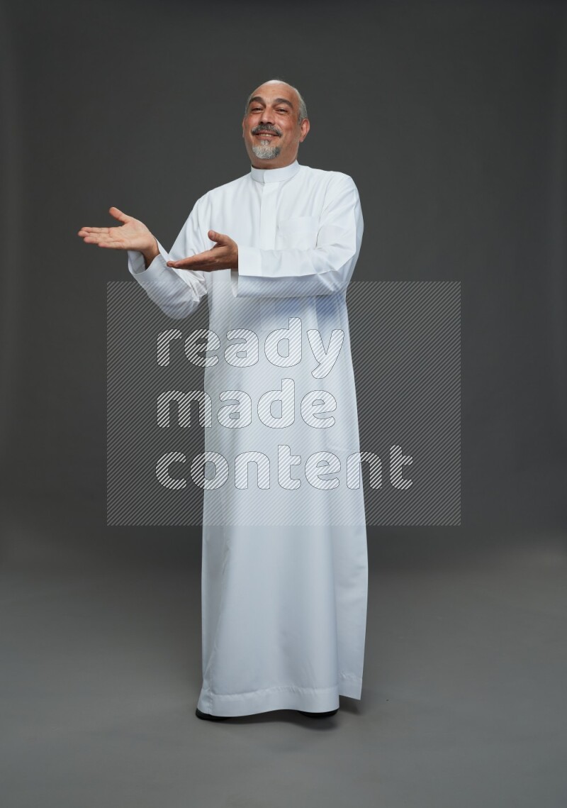 Saudi man without shomag Standing Interacting with the camera on gray background