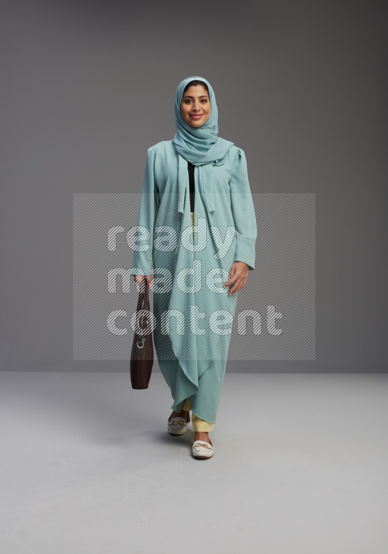 Saudi Woman wearing Abaya standing holding bag on Gray background