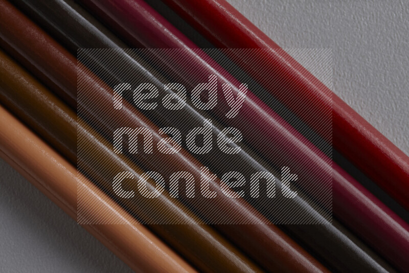 مجموعة من أقلام الرصاص الملونة مرتبة لتعرض تدرجا من الألوان البنية علي خلفية رمادية