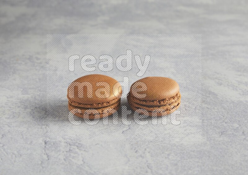 45º Shot of two Brown Coffee macarons  on white  marble background