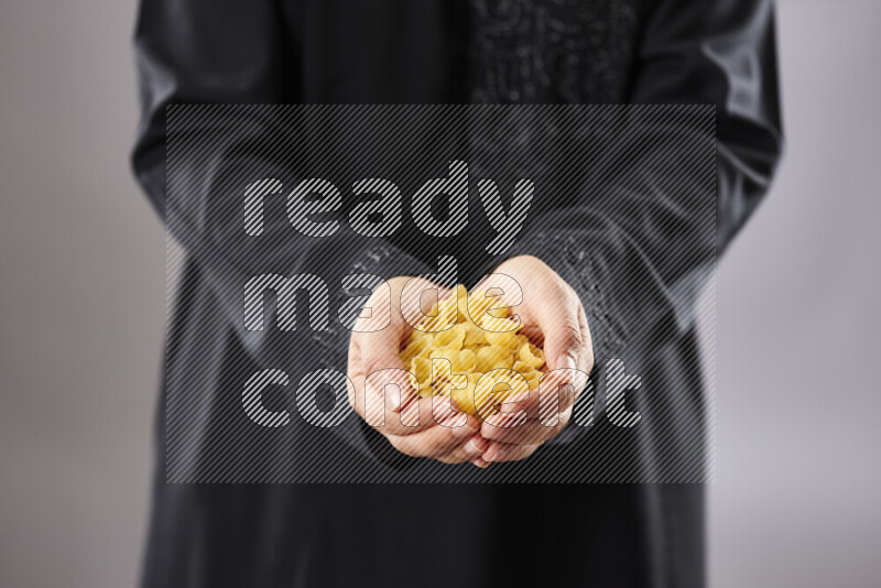 Woman in abaya holding different kinds of pasta in different positions