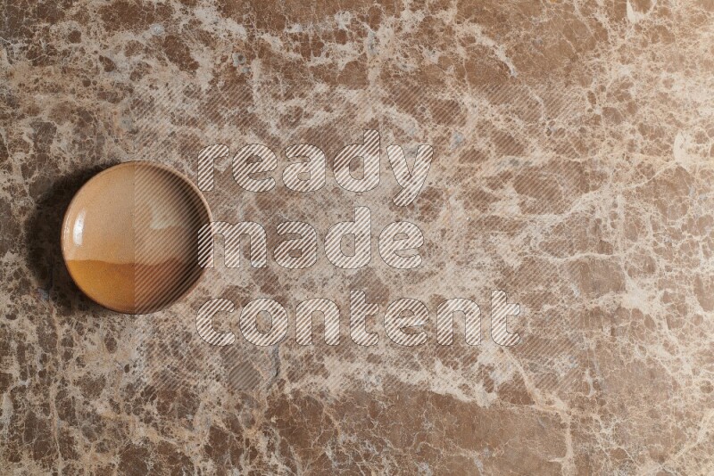 A multicolored pottery plate on beige marble background