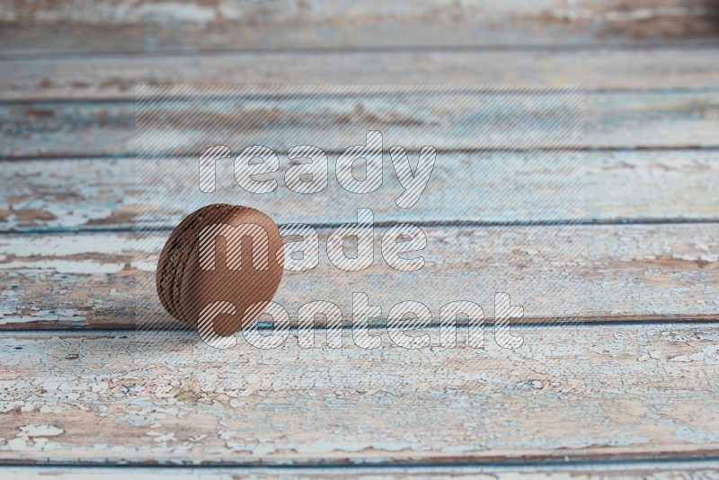 45º Shot of Brown Dark Chocolate macaron on light blue wooden background