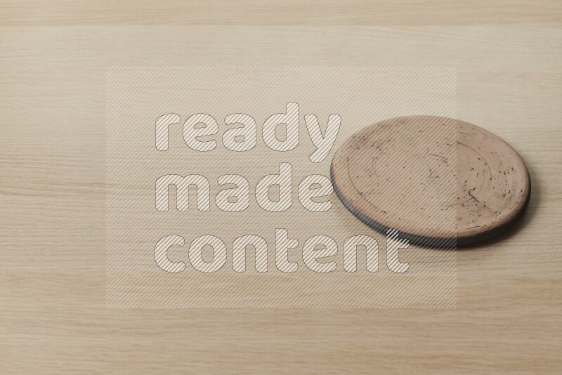 A pottery coaster on light wooden background