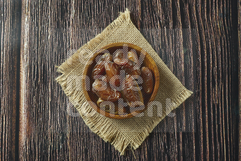 Dates in different bowls (wooden, pottery and glass) on wooden background