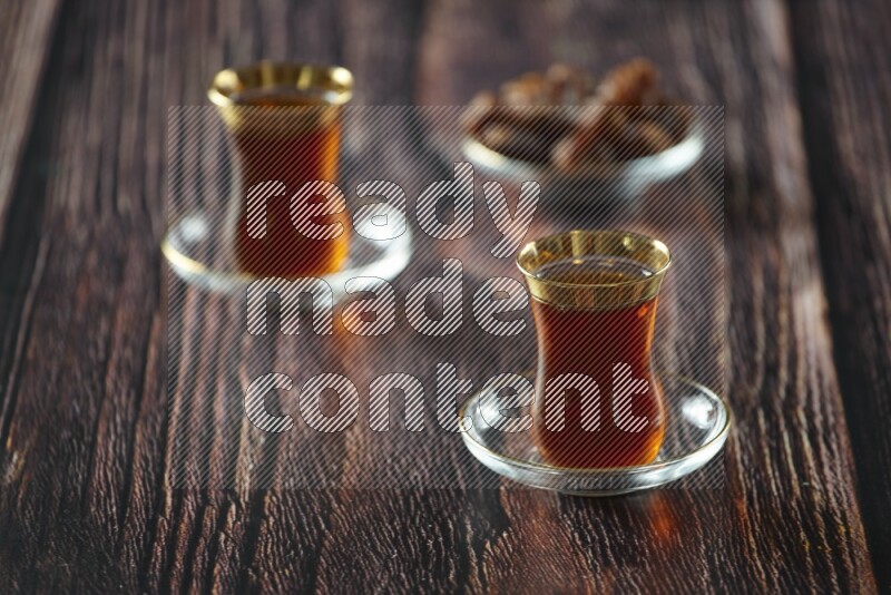 A tea glass cup with dates and coffee on wooden background