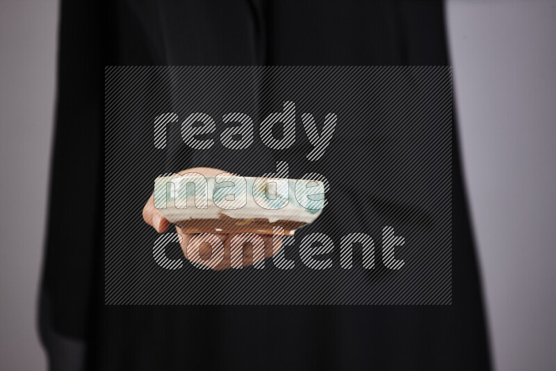 امرأة ترتدي عباءة سوداء تحمل أدوات فخارية مختلفة في أوضاع متعددة