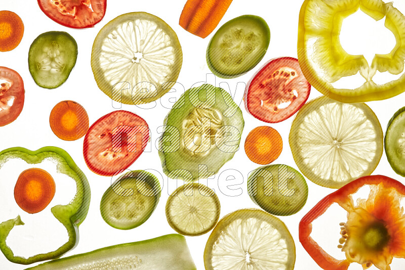 Mixed vegetables and fruits slices on illuminated white background