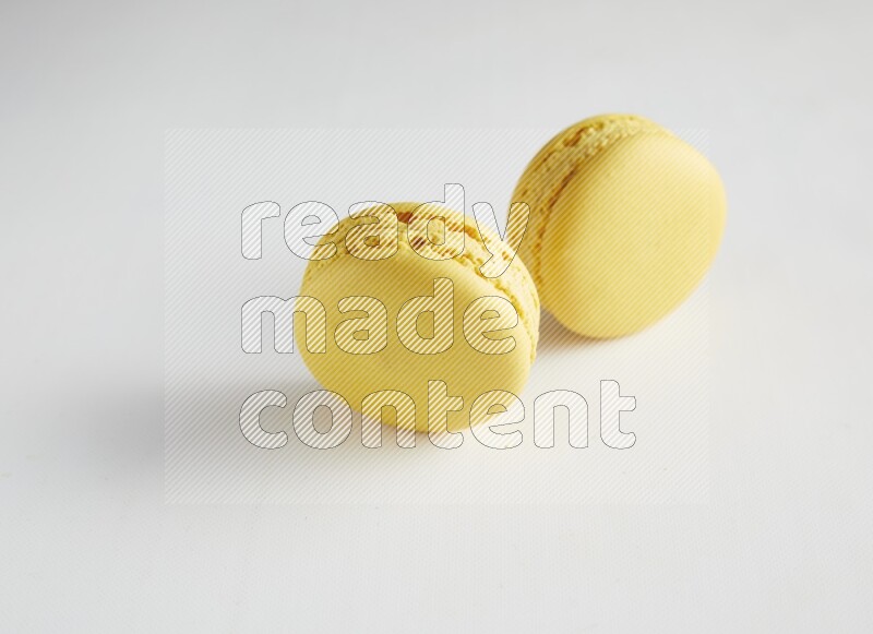 45º Shot of two Yellow Lemon macarons on white background