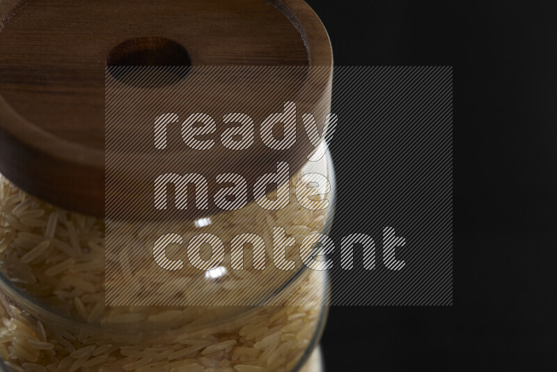 Basmati golden rice in a glass jar on black background