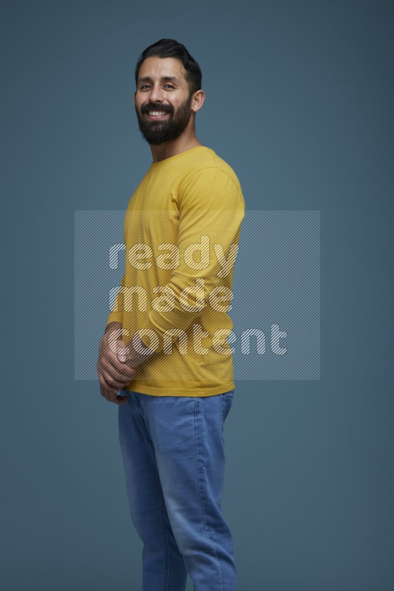 Man posing in a blue background wearing a yellow shirt