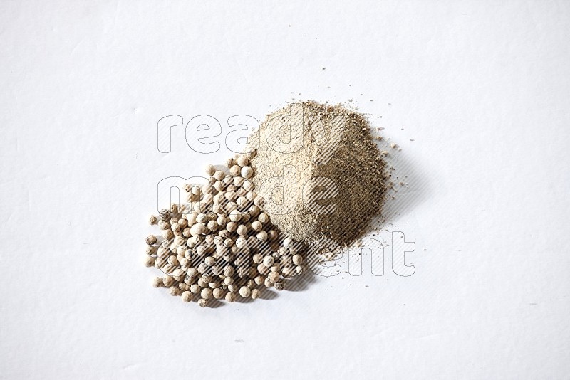White pepper powder and pepper beads on white flooring