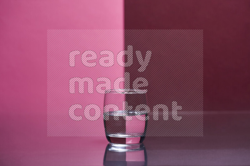 The image features a clear glassware filled with water, set against pink and dark red background