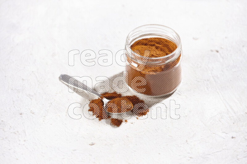 A glass jar full of ground paprika powder on white background