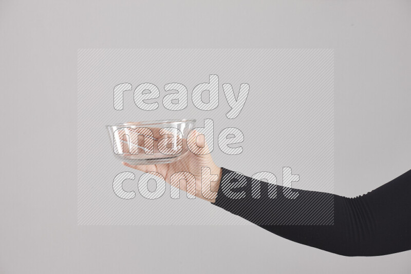 A woman in black abaya holding different glassware in different positions