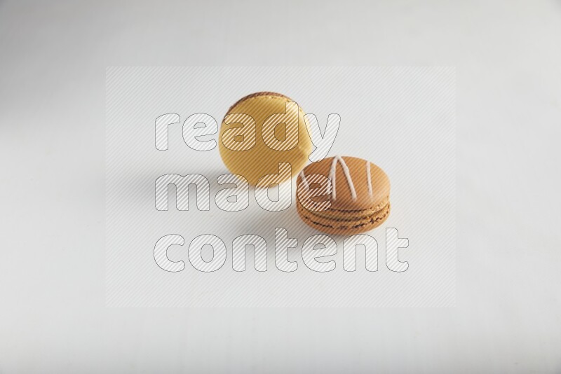 45º Shot of of two assorted Brown Irish Cream, and Yellow, and Brown Chai Latte macarons on white background