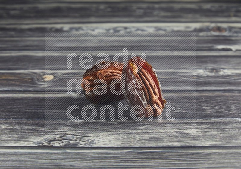 two pecan stuffed madjoul date on a wooden grey background