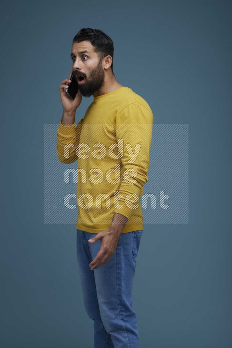 A man having a calling in a blue background wearing a yellow shirt