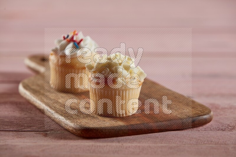 Vanilla mini cupcake topped with white chocolate curls on a wooden board
