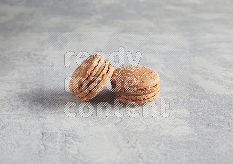 45º Shot of two Brown Hazelnuts macarons  on white  marble background