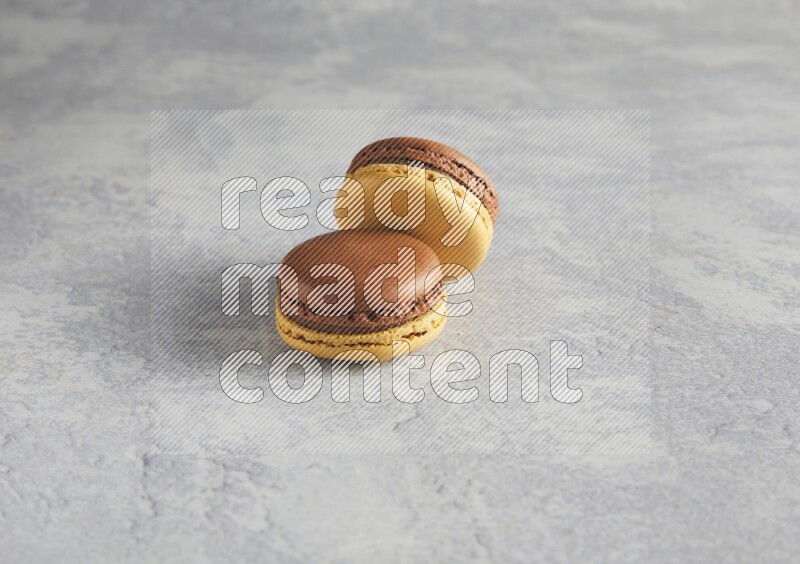 45º Shot of two Yellow and Brown Chai Latte macarons r on white  marble background