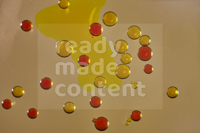 Close-ups of abstract yellow and red watercolor drops on oil Surface on yellow background