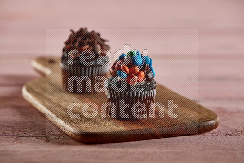 Chocolate mini cupcake topped with m&ms on a wooden board