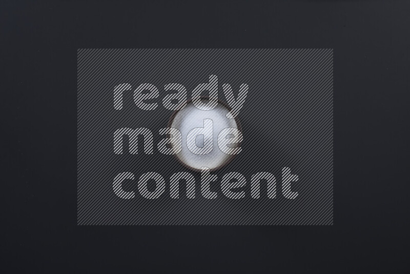 Pottery bowl full of fine table salt and coarse sea salt on black background