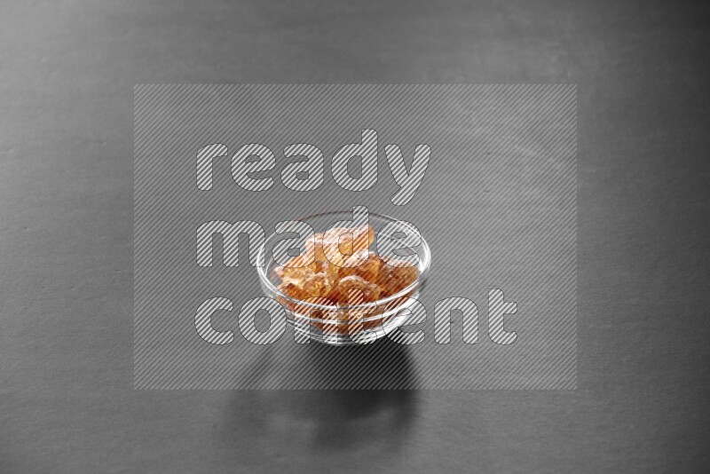 A glass bowl full of gum arabic on black flooring