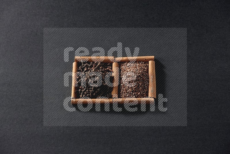 2 squares of cinnamon sticks full of flaxseeds and cloves on black flooring