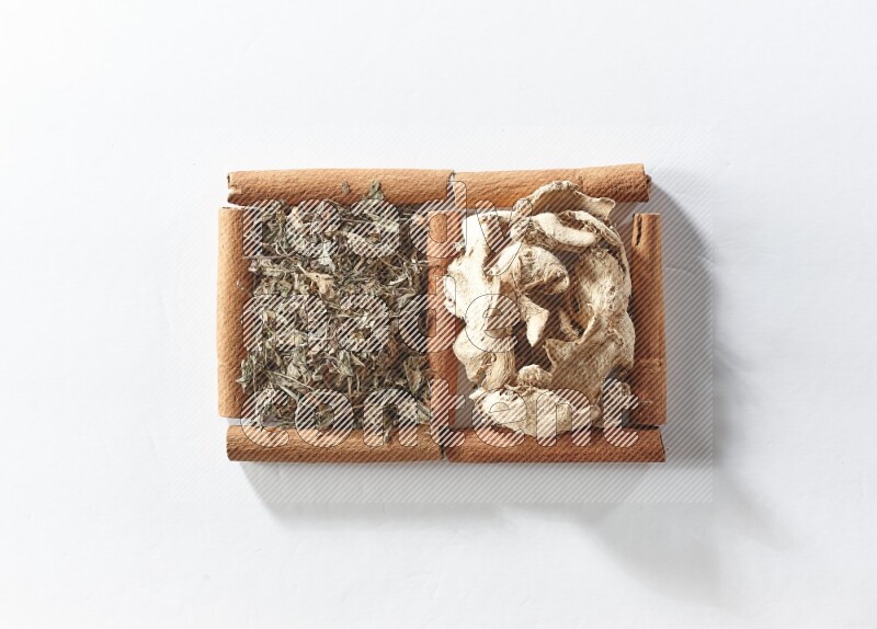 2 squares of cinnamon sticks full of dried ginger and dried basil on white flooring