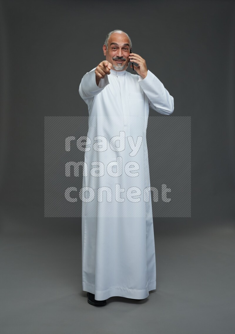 Saudi man without shomag Standing talking on phone on gray background